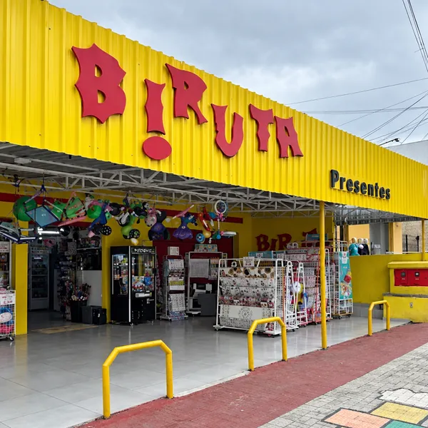 Fachada amarela da Biruta Presentes com o letreiro vermelho